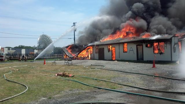 Firefighters direct a master stream at a fully-involved building during live fire training.