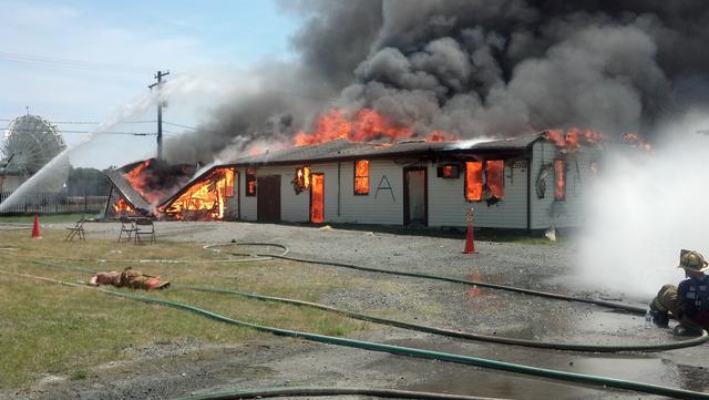 Firefighters coordinate a combination of hose streams to help control a fully-involved building during live fire training.