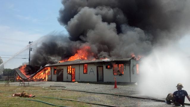 Firefighters coordinate a combination of hose streams to help control a fully-involved building during live fire training.