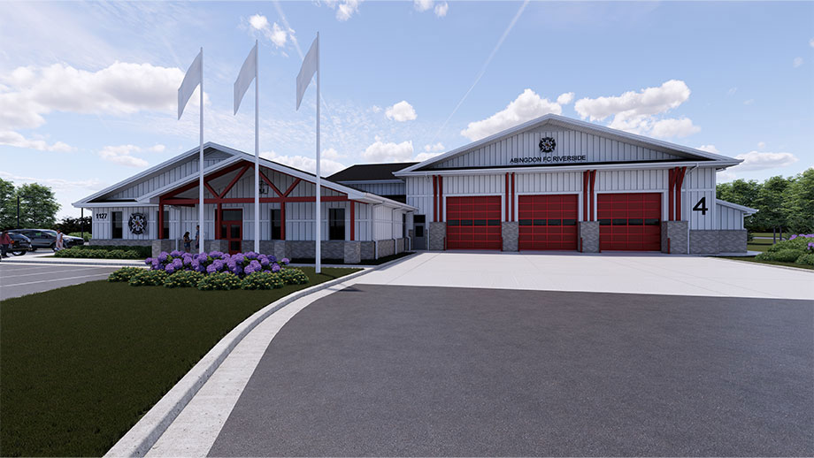 Modern fire station with a white and gray exterior, red accents, four large red garage doors, three flagpoles, a flower bed, and clear skies with scattered clouds in the background.