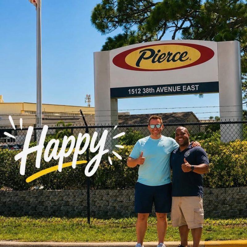 Two smiling men stand in front of a Pierce sign at 1512 38th Avenue East, giving thumbs up. The word “Happy” is written in bold across the image. Trees and a fence are visible in the background.